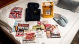 Rundumversorgung: Die Buddies finden auf ihren Zimmern alles, was sie für ein aufregendes, sportliches und entspanntes Wochenende brauchen: Ein kariertes Hemd von Ernsting's Family, eine recycelbare Outdoorjacke der Linie "Pack and Go" von Jack Wolfskin, ein Reiseset von Acqua di Parma und flauschige Hausschuhe von GANT, nebst erstklassiger Lektüre.