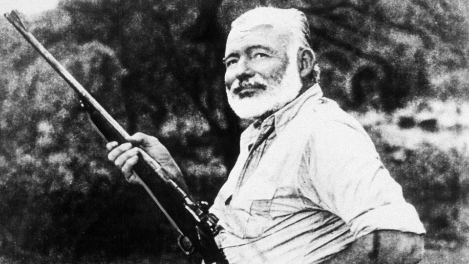 Ernest Hemingway mit Gewehr in der Hand. Neben ihm ein erlegter Jaguar liegend