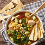 Pozole  Zutaten:  1 kg Eisbein, 500 g flache Bauchrippe, Salz, 3-4 Knoblauchzehen, gepellt, 2 Zwiebeln, geviertelt, 1 daumenballengroßes Stück frische Ingwerwurzel, geschält, 1 TL Pfefferkörner, angedrückt, 1 EL Kreuzkümmelsaat, 1 Dose Pozole-Mais (650 g Abtropfgewicht), 700 g Nackensteak, 1 Glas grüne oder rote, eingelegte Chilischoten, 3-5 Ancho-Chilis, ½ rote Zwiebel, 1 EL Essig, 2 Bund Radieschen, ½ Spitzkohl, 2 Bund Koriandergrün, 4–5 Limetten  Zubereitung:  Das Eisbein und die Rippen in einen großen (!) Topf geben und mit Wasser bedecken, leicht salzen, einmal aufkochen und wiederholt mit einer Schaumkelle abschäumen. Nach dem Abschäumen 2 Knoblauchzehen, 2 Zwiebeln, Ingwer, Pfefferkörner und Kreuzkümmelsaat zum Fleisch geben. Die Hitze herunterschalten und das Fleisch 2 Stunden sanft ziehen lassen.  Während das Fleisch gart, den Pozole-Mais in einem Sieb unter fließendem Wasser gründlich abspülen, in einen zweiten Topf geben, mit Salzwasser bedecken und ca. 1 Stunde sanft kochend garen.  Eisbein und Rippchen aus dem Topf heben und zum Auskühlen in einem Durchschlag übers Küchenbecken hängen. Die Brühe durch ein Sieb in eine Schüssel gießen. Nur den Ingwer würfeln und beiseite legen, die restlichen ausgekochten Gewürze wegwerfen. Die Brühe zurück in den Topf gießen und erhitzen (Trübstoffe am Schüsselboden zurückhalten). Die Nackensteaks im Ganzen in die Brühe und diese nur noch ziehen (nicht kochen) lassen, das Fleisch 30–45 Minuten (je nach Qualität) garen. Den getrennt gegarten Mais durchs Sieb abschütten und in die Brühe geben.  Die  Schwarte vom Eisbein entfernen und entsorgen; das Fleisch vom Knochen lösen, dabei Fett und Bindegewebe abstreifen und entsorgen. Fleisch in grobe Stücke schneiden. Rippchen in Stücke schneiden, Knorpel und Knochen zum späteren Abknabbern dranlassen. Nackensteak aus der Brühe nehmen, in Würfel schneiden und mit Eisbein- und Rippchen zum Eintopf geben. Eingelegte Chilischoten abgießen, die Schoten grob zerschneiden und mit dem Ingwer in den Eintopf geben (die Qualität der Schoten bestimmt die Schärfe des Eintopfes).  3–5 Ancho-Chilis aufschlitzen und entkernen, das Fruchtfleisch ca. 15 Minuten in etwas Wasser köcheln, dann mit 1–2 Knoblauchzehen, 1/2 roten Zwiebel, 1 EL Essig und 1 TL Salz pürieren; 250 ml von der Brühe dazugeben und verrühren.  Radieschen in Scheiben schneiden. Spitzkohl vierteln und in feine Streifen schneiden. Koriandergrün von den Stielen zupfen. Limetten vierteln. Den Eintopf in Schalen servieren und mit Radieschen, Kohlstreifen und Koriander garnieren. Limettenviertel darüber ausdrücken. Mit den pürierten Ancho-Chilis würzen.  Tipp: Zum Eintopf dünnes Fladenbrot reichen (Tortillas, Chubz oder Lawasch – letztere sind arabische bzw. persische Brote, gibt's im türkischen Lebensmittelhandel).