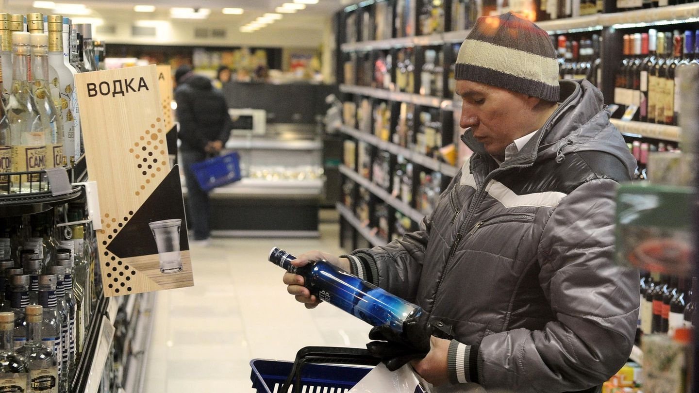 Russland, Moskau: Ein Mann legt in einem Geschäft eine Flasche Wodka in seinen Einkaufskorb