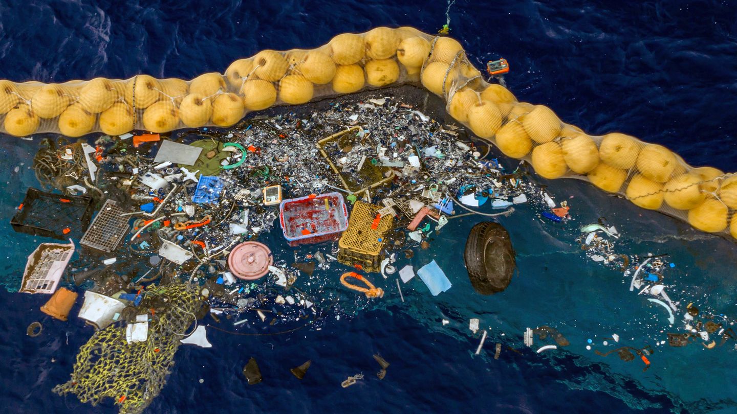 Plastikstücke schwimmen vor einer Dichtung im Meer