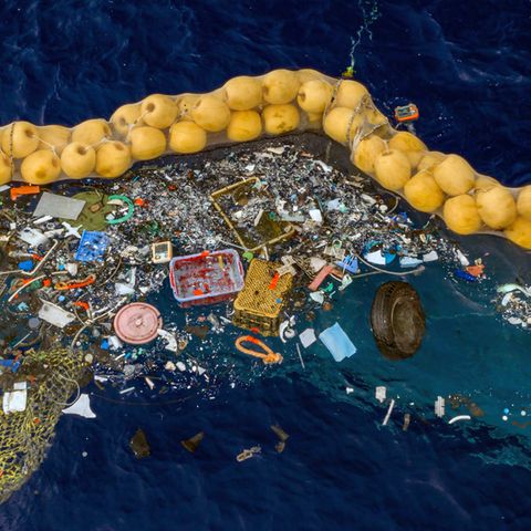 Plastikstücke schwimmen vor einer Dichtung im Meer