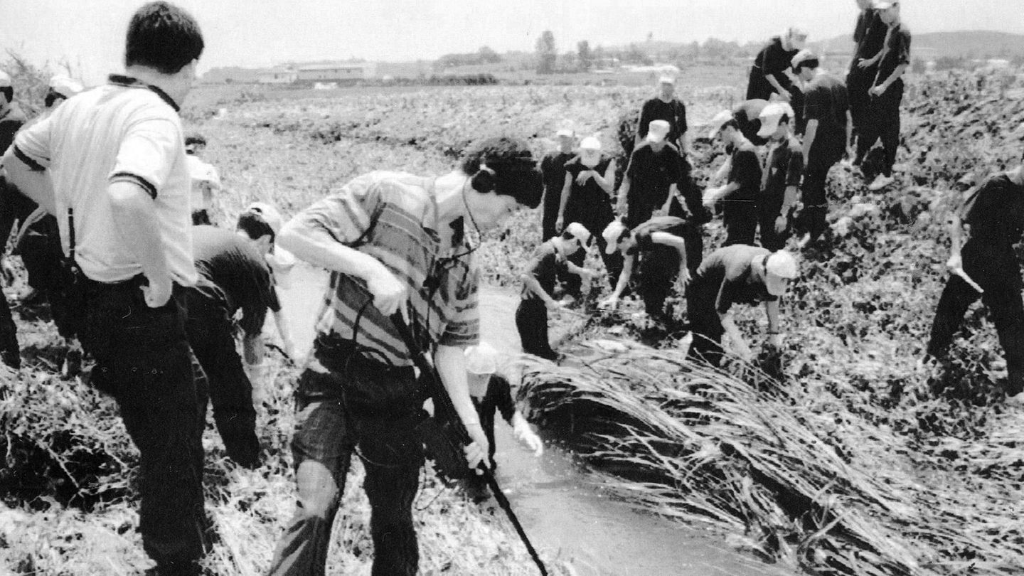 Auf einem Schwarz-weiß-Foto stehen koreanische Ermittler an einem Wassergraben und untersuchen den Tatort