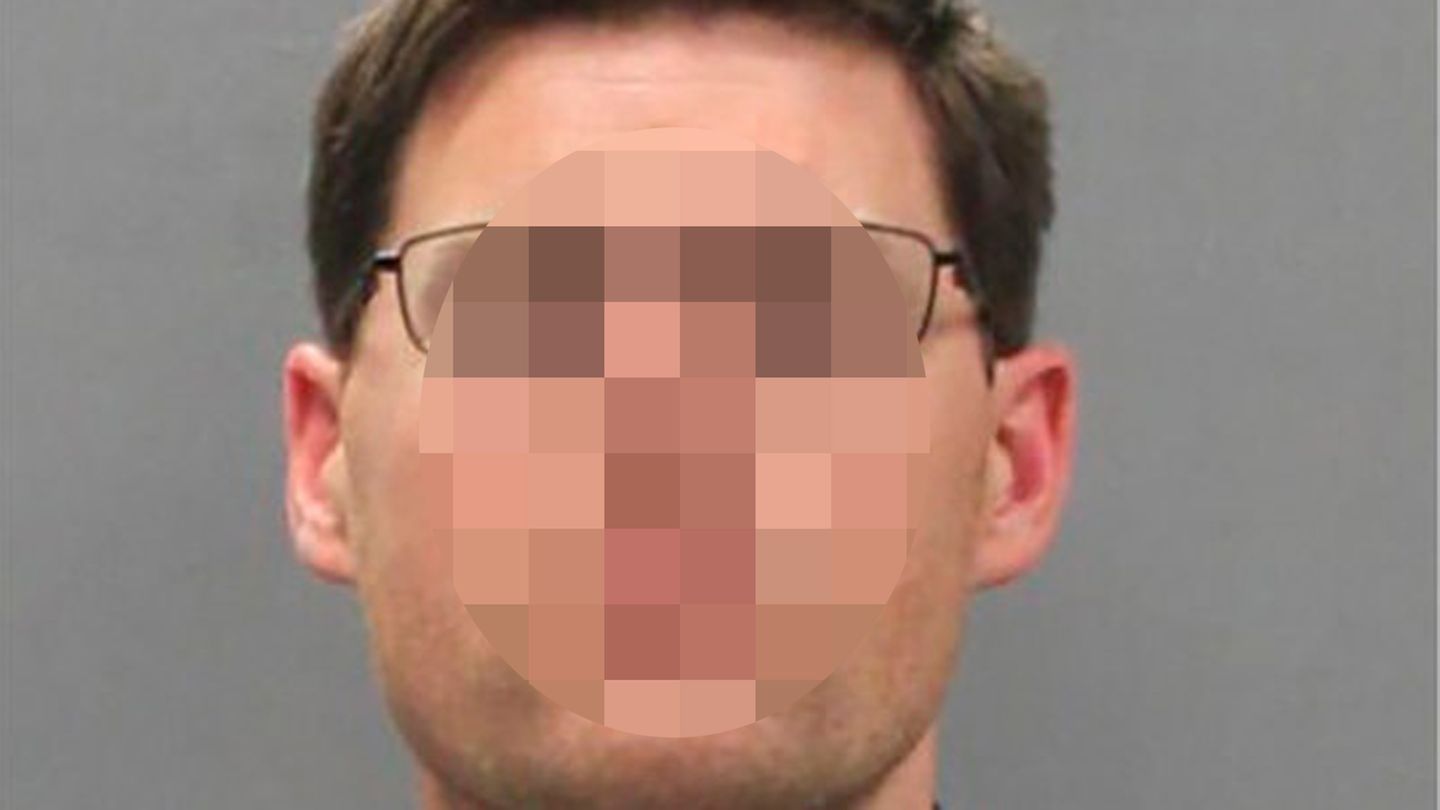 Ein Mann mit dunkelblondem Seitenscheitel, Brille und blau-grauem Karohemd schaut gerade in die Kamera