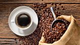 Kaffeepulver: Eine Tasse Kaffee und Kaffeebohnen auf einem Tisch