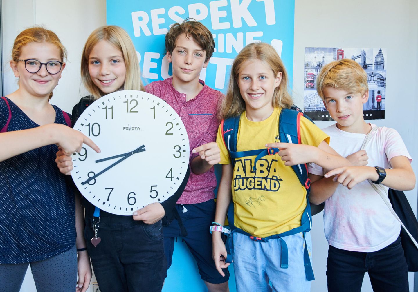 Schüler zeigen auf eine Uhr, die 8.40 Uhr zeigt