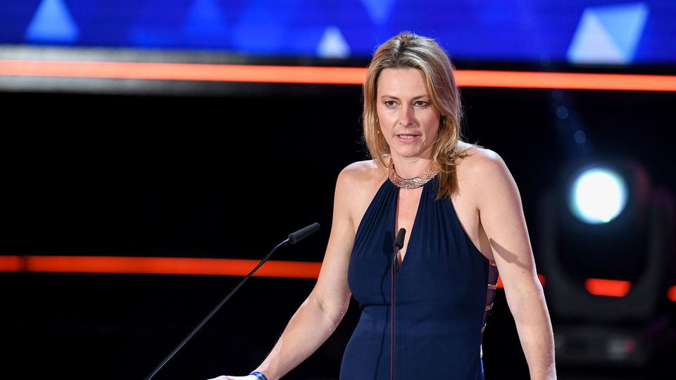 Die blonde Moderatorin Anja Reschke steht in schwarzem Abendkleid an einem Rednerpult und spricht in zwei Mikrofone