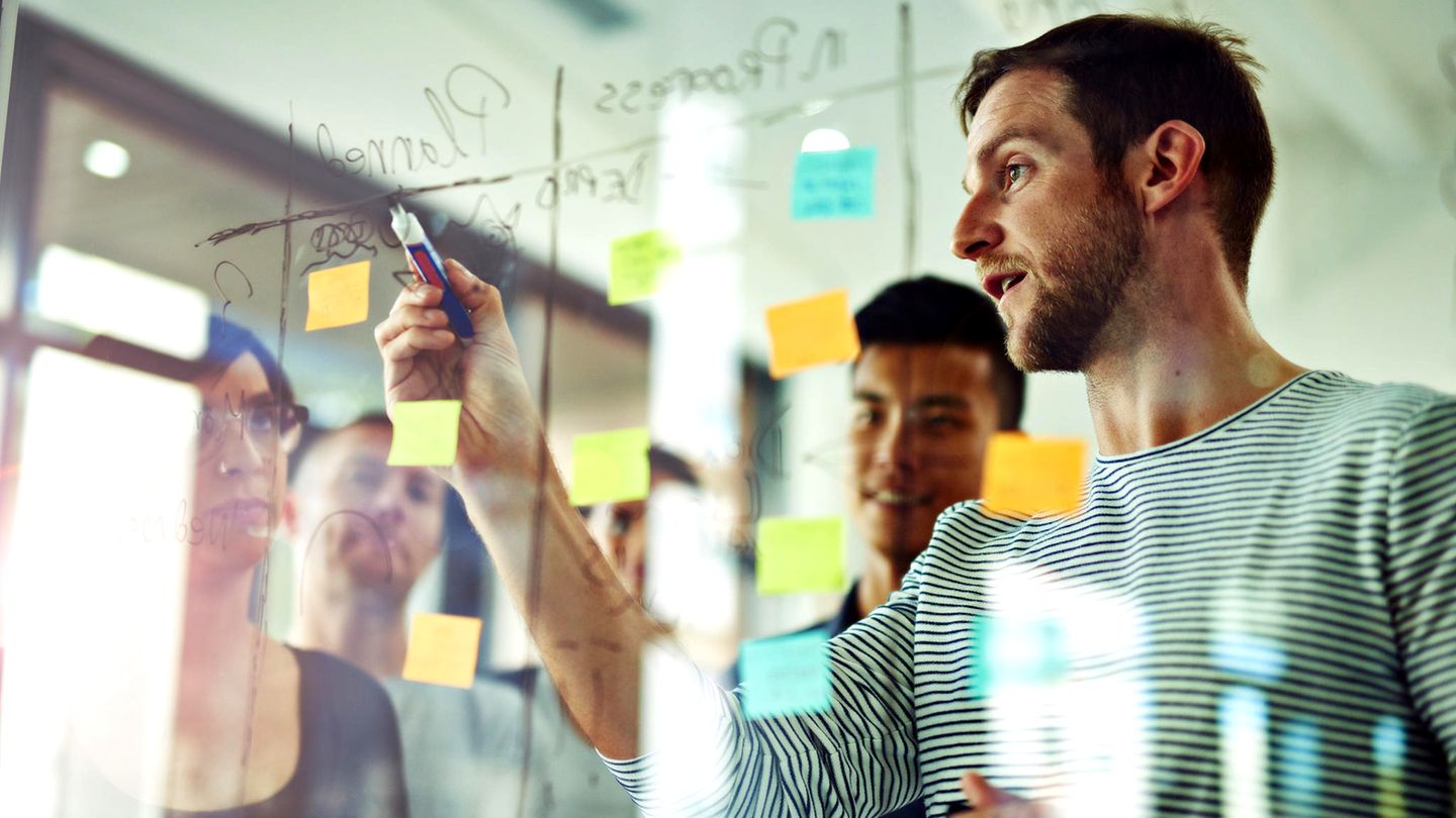Meeting vor einem transparenten Glasboard