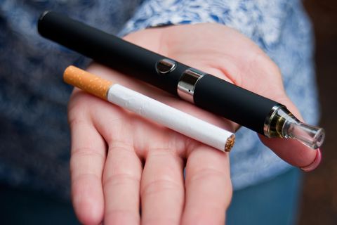 E-Zigarette: Eine Frau hält eine Zigarette und eine E-Zigarette in der Hand