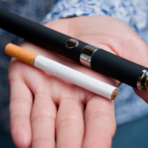 E-Zigarette: Eine Frau hält eine Zigarette und eine E-Zigarette in der Hand