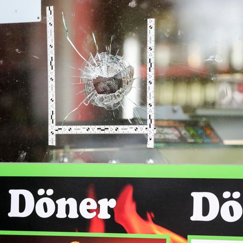 Markierungen der Polizei kleben um einen Einschuss in der Schaufensterscheibe eines Dönerladens in Halle