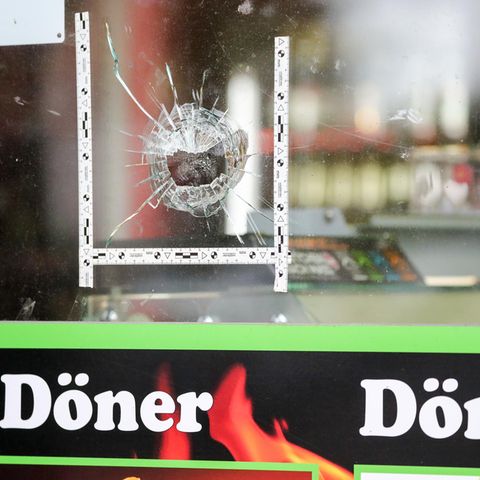 Markierungen der Polizei kleben um einen Einschuss in der Schaufensterscheibe eines Dönerladens in Halle