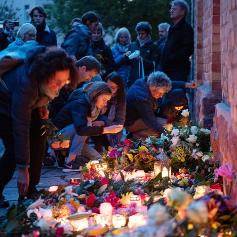 Trauernde legen an der Mauer der Synagoge Blumen nieder und zünden Kerzen an