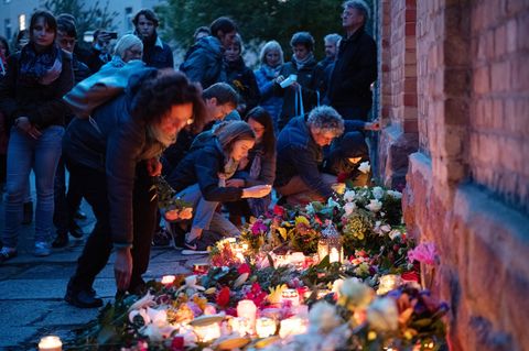 Trauernde legen an der Mauer der Synagoge Blumen nieder und zünden Kerzen an