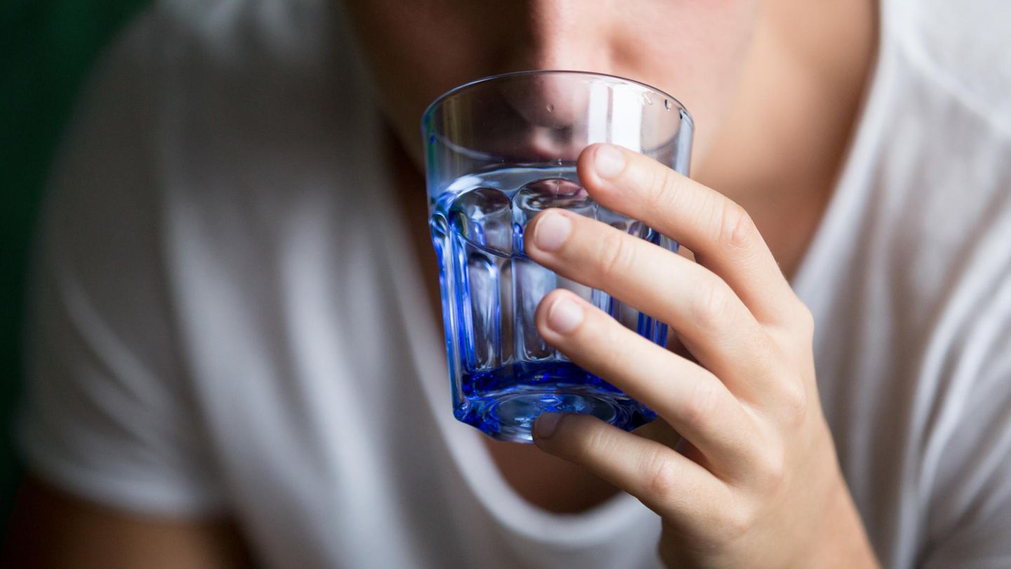 Ein Mann schluckt mit Wasser eine Pille herunter