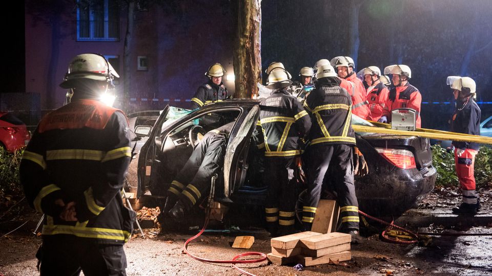 Hamburg: Einsatzkräfte der Feuerwehr arbeiten nach einem Verkehrsunfall an einem Autowrack