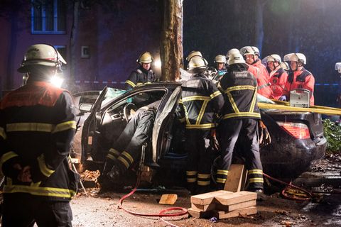 Hamburg: Einsatzkräfte der Feuerwehr arbeiten nach einem Verkehrsunfall an einem Autowrack