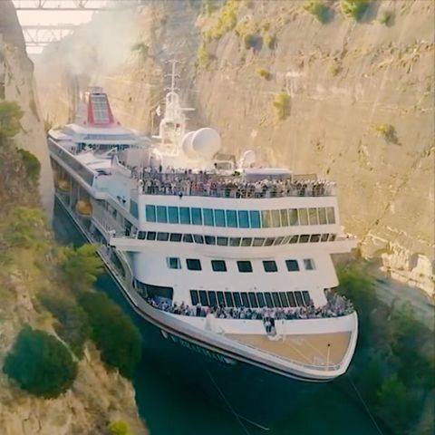 Ein Kreuzfahrtschiff fährt durch einen sehr engen Kanal mit behauenen Felswänden