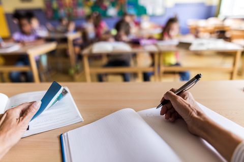 Eine Lehrerin sitzt vor einer Grundschulklasse