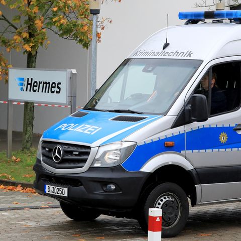 Ein Polizeiauto von der Kriminaltechnik fährt auf das Gelände des Paketdienstleisters Hermes