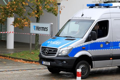Ein Polizeiauto von der Kriminaltechnik fährt auf das Gelände des Paketdienstleisters Hermes