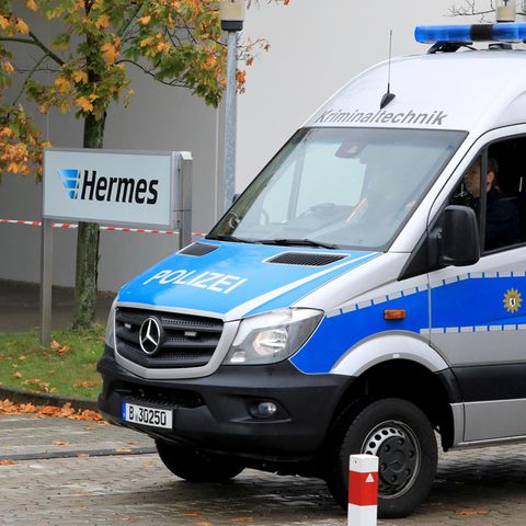 Ein Polizeiauto von der Kriminaltechnik fährt auf das Gelände des Paketdienstleisters Hermes