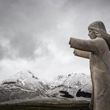 Im Vordergrund: Die Statue einer Frau. Im Hintergrund: Schneebedecktes Gebirge