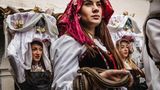 Junge Frauen in Tracht und mit Schlangen in den Händen