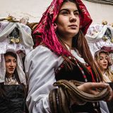 Junge Frauen in Tracht und mit Schlangen in den Händen