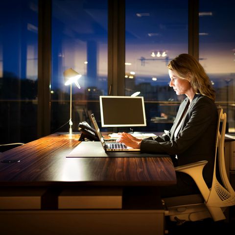 Frau sitzt abends im Büro
