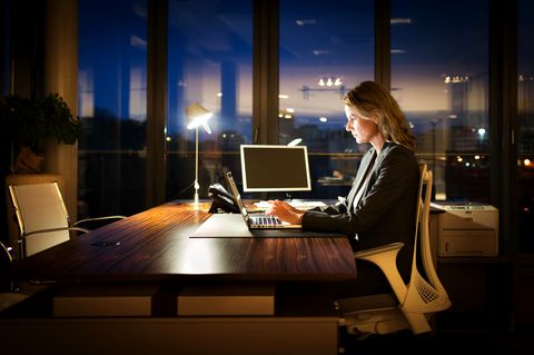 Frau sitzt abends im Büro