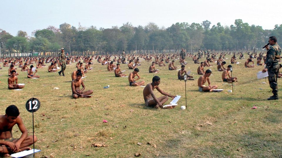 Bis auf die Unterhose entkleidet schreiben indische Rekruten ihre Prüfung bei der Armee