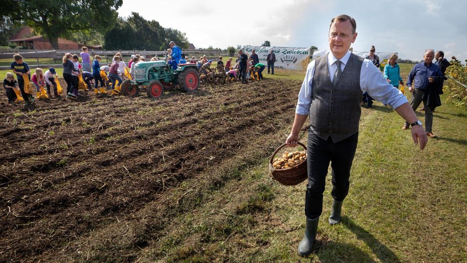 10.09.2019, Thüringen, Heichelheim: Bodo Ramelow (Linke), Thüringens Ministerpräsident, geht mit einem Korb selbst geernteter Kartoffeln an einem Feld vorbei. Für Thüringer Kartoffelbauern zeichnet sich erneut kein gutes Jahr ab, fehlender Regen in der ... Ministerpräsident Ramelow mit einem Korb selbst geernteter Kartoffeln auf einem Feld in Heichelheim