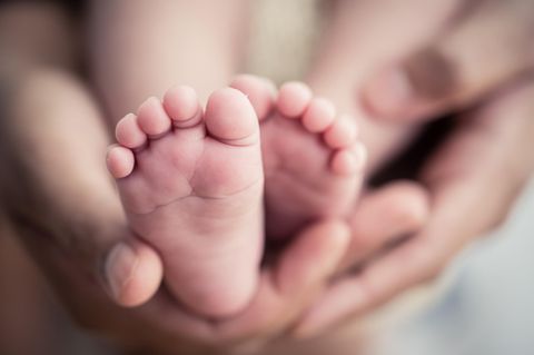 Eine Mutter hält ein Neugeborenes in der Hand