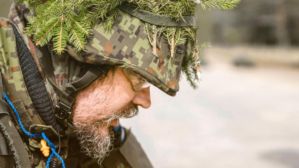 Allan durchsucht einen Gegner, der bei einer Übung der estnischen Selbstverteidigungsgruppen Kaitseliit (Tartu Unit) getroffen wurde nahe Tammsalu, Estland (darf das genannt werden?). Ein Soldat mit Tannenzweigen auf dem Helm