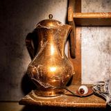 Eine verstaubte Karaffe. Daneben ein Kunstauge in einem blutigen Löffel