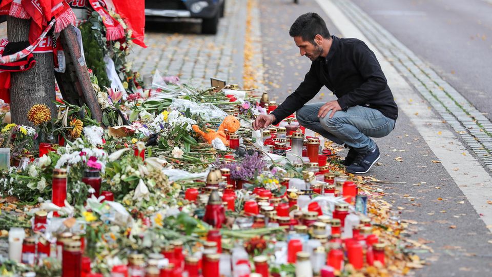 Izzet Cagac, Betreiber des Kiez-Döners, hockt vor dem Meer aus Kerzen und Blumen vor seinem Imbiss