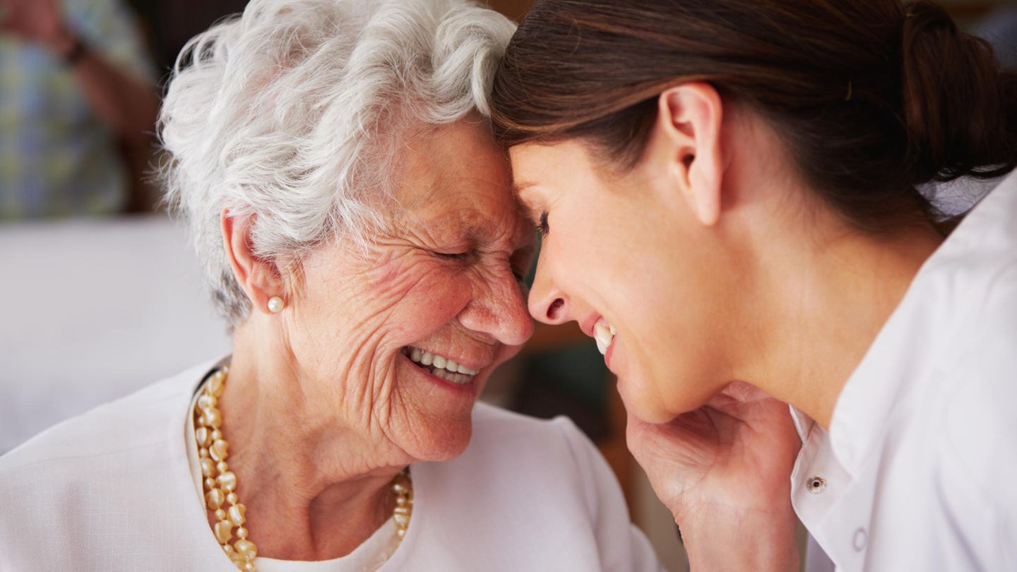 Eine Seniorin lacht gemeinsam mit einer Pflegerin