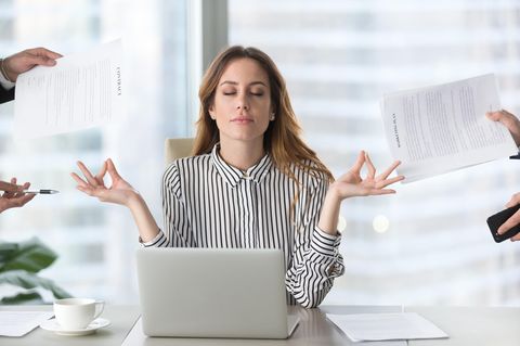 Eine Frau sitzt offensichtlich tiefenentspannt vor ihrem Laptop am Schreibtisch und bekommt von allen Seiten Aufgaben zugeteilt