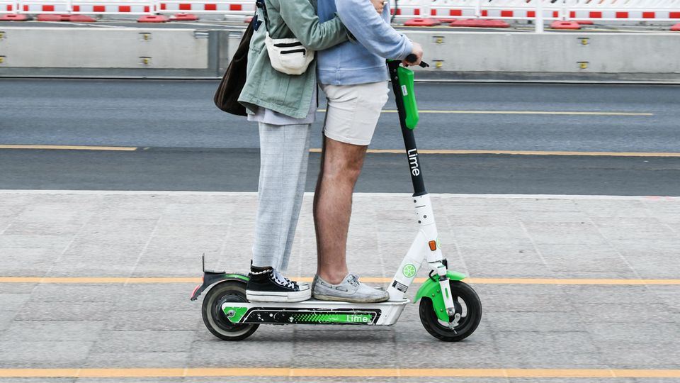 Zwei Personen fahren gemeinsam gleichzeitig auf einem E-Tretroller