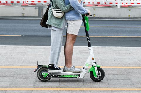 Zwei Personen fahren gemeinsam gleichzeitig auf einem E-Tretroller