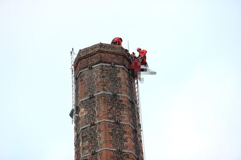 Einsatzkräfte bergen den leblosen Körper des Mannes von dem mehr als 80 Meter hohen Schornstein