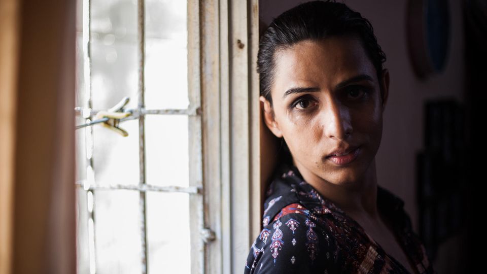 Eine junge Transgender-Frau steht an einem Fenster