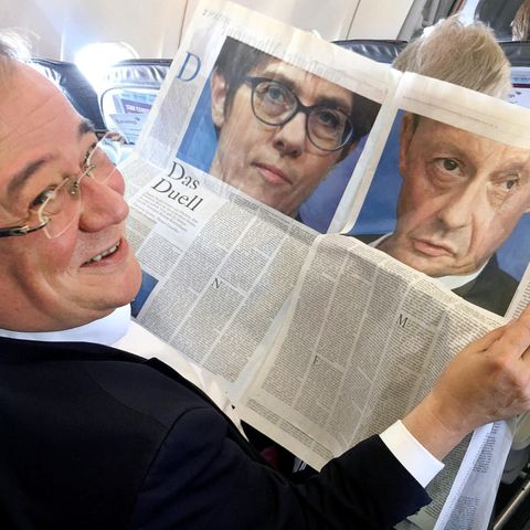 NRW-Ministerpräsident Armin Laschet liest im Flugzeug einen Zeitungsartikel über "Das Duell" zwischen AKK und Merz