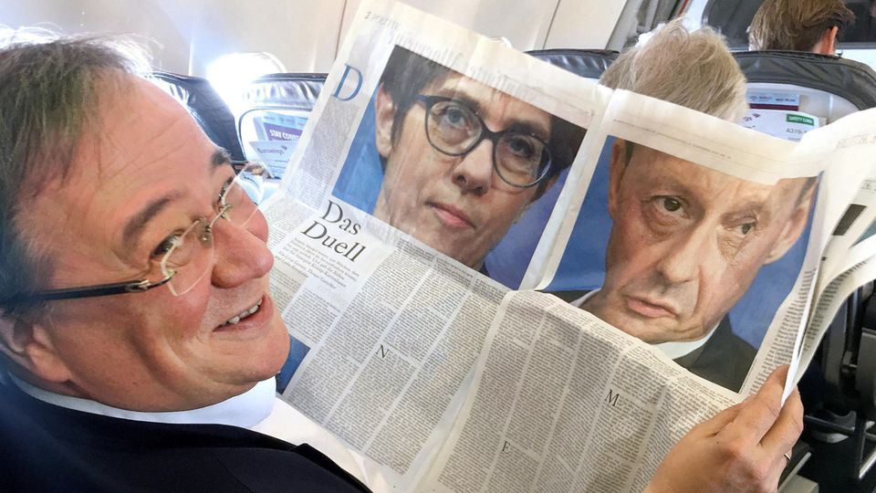 NRW-Ministerpräsident Armin Laschet liest im Flugzeug einen Zeitungsartikel über "Das Duell" zwischen AKK und Merz