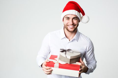 Lächelnder Mann in Nikolausmütze mit Geschenk-Boxen