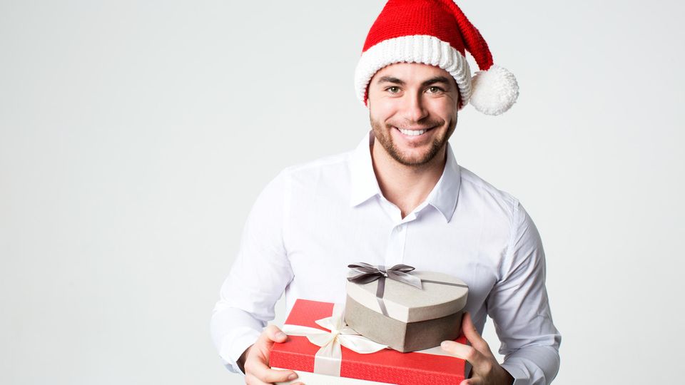 Lächelnder Mann in Nikolausmütze mit Geschenk-Boxen