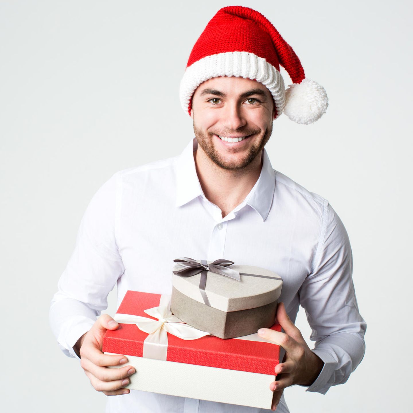 Lächelnder Mann in Nikolausmütze mit Geschenk-Boxen