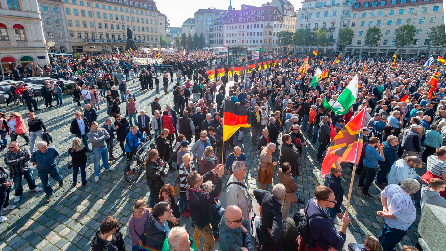 Teilnehmer einer Kundgebung von Pegida und Teilnehmer von Gegenkundgebungen stehen auf dem Altmarkt in Dresden