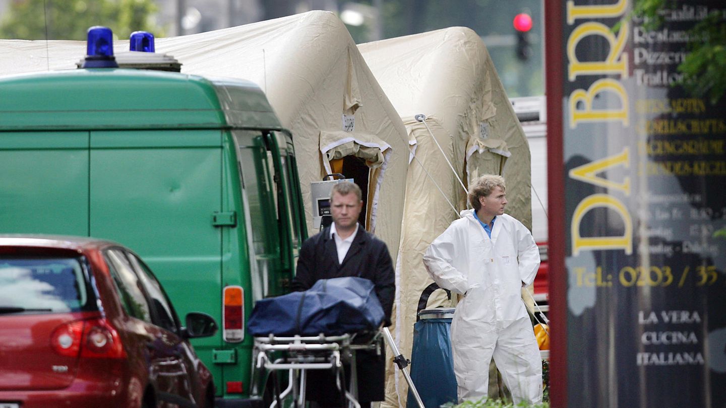 Ein Bestatter schiebt eine Trage mit einer verdeckten Leiche von einem Tatort